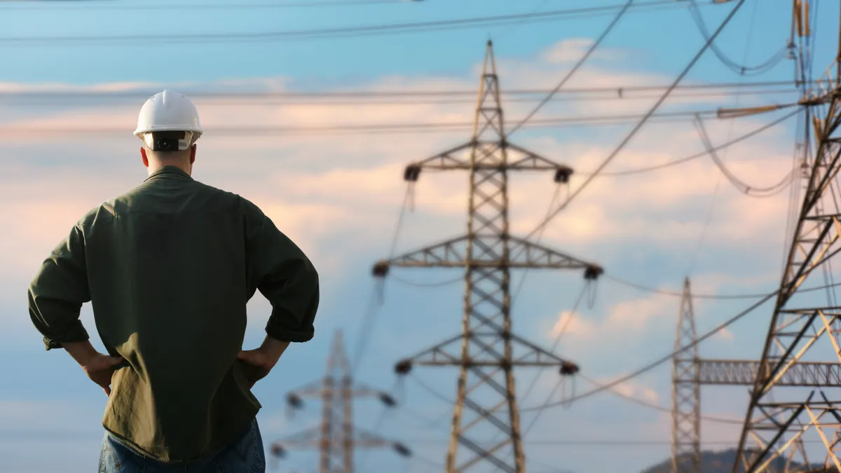 Power line and worker over sky.